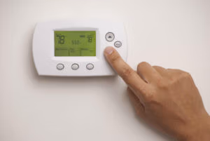 Homeowner looking at thermostat to see if they have heat pump