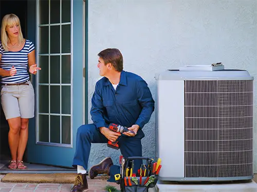 Air conditioning service technician inspecting an outdoor AC unit at a Texas home